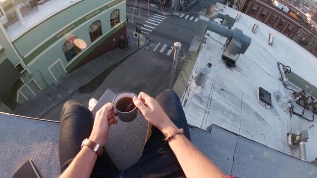 Tilt up POV, man drinks coffee on San Francisco rooftop