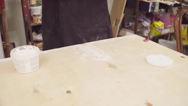 High angle view. Close up hands of senior carpenter spackling wooden board