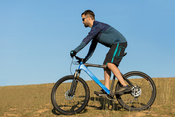 Cyclist in shorts and jersey on a modern carbon hardtail bike with an air suspension fork	