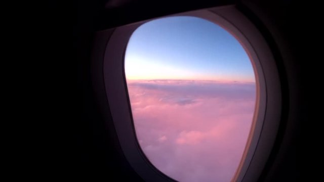 Plane flies over colorful clouds at sunset, POV