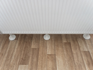Close up of radiator with feet on vinyl wooden flooring and cut out holes gone wrong, reason for...
