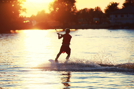 Wakeboarder surfing the lake on a warm summer evening
