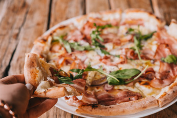 Woman's hand grab slice of pizza