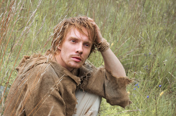 young shaggy and unshaven guy dressed as a medieval peasant from an old bag thought about something...