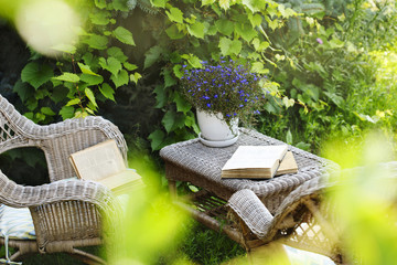 Wicker table, chairs and books in the garden at summer time