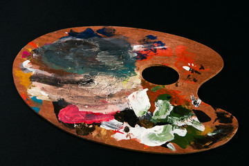 Art Palette and paint brush on black background, close-up.