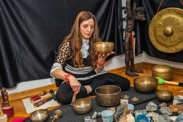 Woman playing a singing bowls also known as Tibetan Singing Bowls, Himalayan bowls. Tibetan Singing...