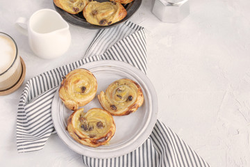 French breakfast - pain aux raisins, cappuccino, milk pitcher, coffe maker. Flat lay.