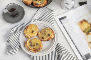 French breakfast concept - pain aux raisins, coffee, striped crumpled napkin.