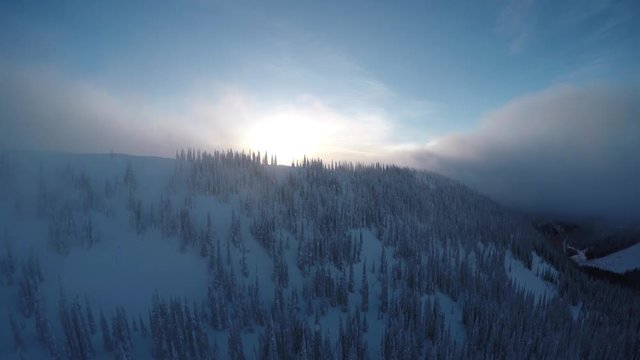 Wide aerial, clouds roll over snowy mountains in British Columbia