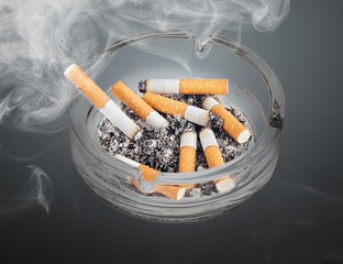 Burning cigarettes in ashtray on white background