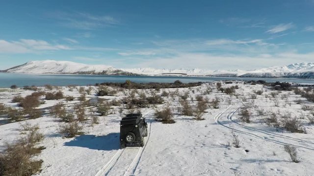 Car drives off-road in winter landscape, aerial