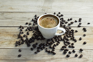 Cup of coffee and coffee beans on wooden background.