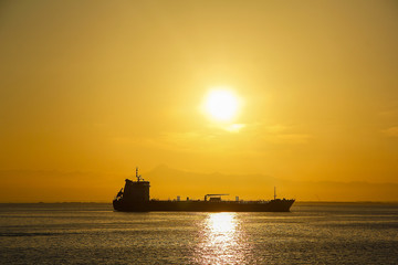 Cargo ship at sunrise with a big sun