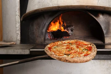 Crédence de cuisine en verre imprimé Pizzeria Mettre une pizza savoureuse au four dans la cuisine du restaurant