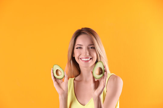 Portrait of young beautiful woman with ripe delicious avocado on color background
