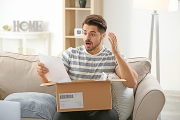 Young man unpacking parcel at home