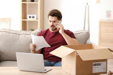 Young man making call about delivered parcel at home