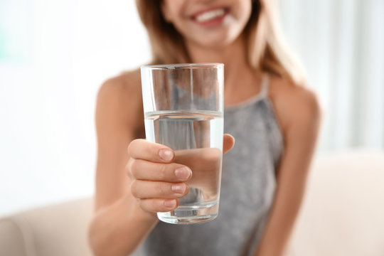 Woman holding glass with clean water at home, closeup