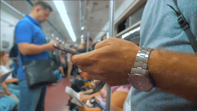Casual man reading from mobile phone smartphone screen while looks the navigator traveling on metro in the subway. lifestyle slow motion video. Wireless internet on public transport concept. man in