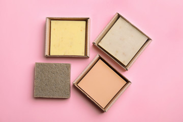 Hand made soap bars in cardboard packages on color background, top view