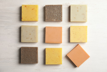 Hand made soap bars on white wooden background, top view