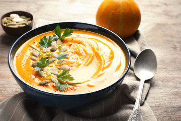 Delicious pumpkin cream soup in bowl on wooden table
