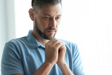 Naklejka premium Man with hands clasped together for prayer on light background. Space for text