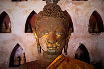 gold plated theravada buddhist statues at a monastery with a orange silk cloth
