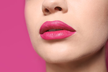 Beautiful young woman with perfect lips makeup on color background, closeup