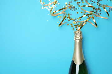 Creative flat lay composition with bottle of champagne and space for text on color background