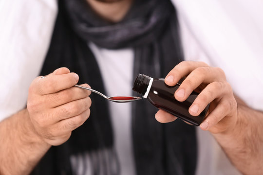 Ill Young Man Taking Cough Syrup, Closeup