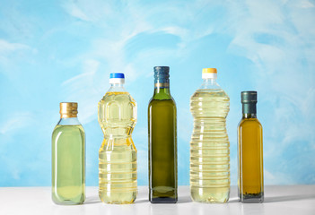 Bottles of oils on table against color background