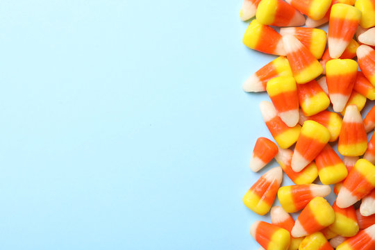 Colorful candy corns and space for text on color background, top view