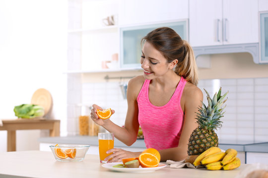 Woman making orange juice at table in kitchen. Healthy diet