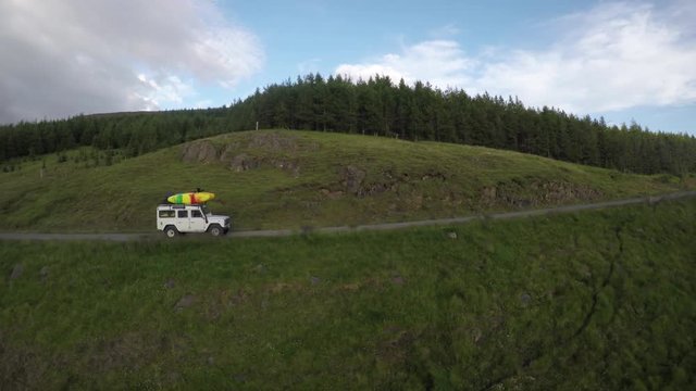Aerial, car drives through lush Iceland landscape
