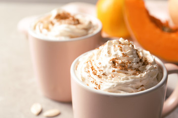 Cup with tasty pumpkin spice latte on gray table, closeup