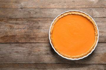 Fresh delicious homemade pumpkin pie on wooden background, top view with space for text