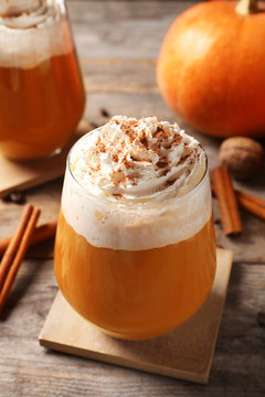 Glass with tasty pumpkin spice latte on wooden table
