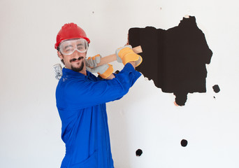 young worker with a red protection helmet and wearing a blue boiler suit. demolition concept