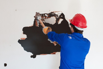 young worker with a red protection helmet and wearing a blue boiler suit. demolition concept