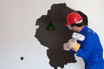 young worker with a red protection helmet and wearing a blue boiler suit. demolition concept