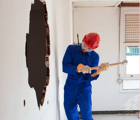 young worker with a red protection helmet and wearing a blue boiler suit. demolition concept