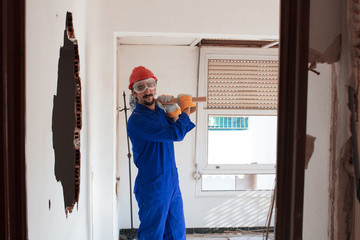 young worker with a red protection helmet and wearing a blue boiler suit. demolition concept