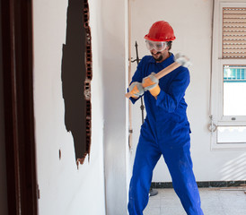 young worker with a red protection helmet and wearing a blue boiler suit. demolition concept