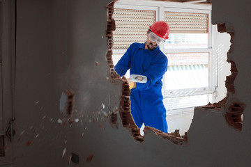 young worker with a red protection helmet and wearing a blue boiler suit. demolition concept