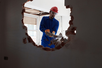 young worker with a red protection helmet and wearing a blue boiler suit. demolition concept
