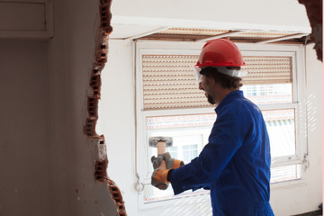 young worker with a red protection helmet and wearing a blue boiler suit. demolition concept