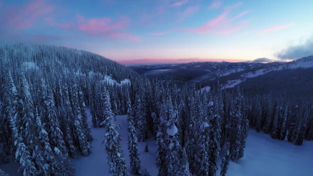 Aerial, colorful sunset over snowy mountain landscape