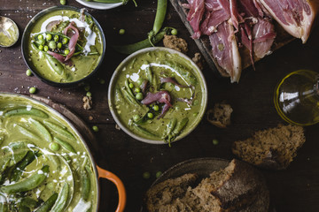 Bowls of green pea soup on a wooden table